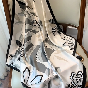 Detail showing the floral print silk scarf draped over a chair with soft texture and folds