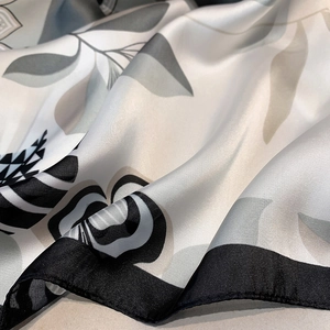 Detailed close-up showing glossy satin texture and abstract floral print of the scarf