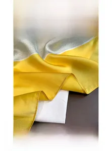 Detailed close-up of fine hand-rolled edges on a yellow and grey silk satin square scarf