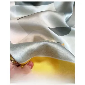 Detailed macro view of digital print texture on yellow and gray silk-like scarf