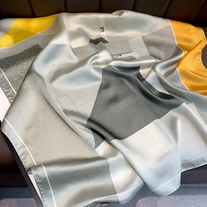 Modern geometric silk-like square scarf with yellow and grey blocks on leather