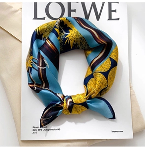 Detail shot of silk scarf with floral print tied in a bow over a fashion magazine