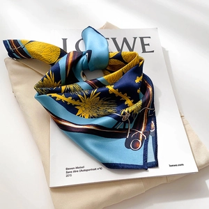 Floral print silk scarf in navy and yellow silk satin, folded elegantly on a magazine