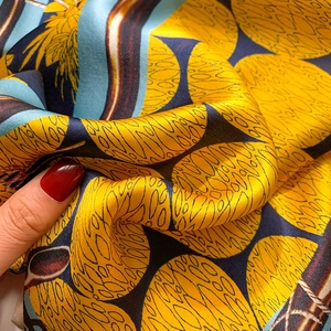 Close-up of silky silk scarf with blue and yellow wavy patterns and fine print detail