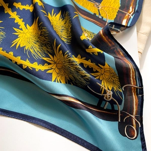 Close-up of silk scarf with botanical patterns and vibrant navy blue and gold satin finish