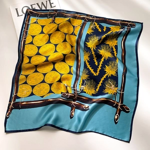 Detailed flat lay of a silk square scarf with blue thistle floral and yellow polka patterns