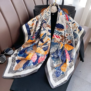 Close-up of luxury floral print scarf draped on a bag with elegant satin texture