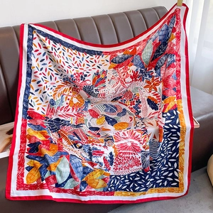 Detailed view of floral print silk scarf with vibrant red borders on leather surface