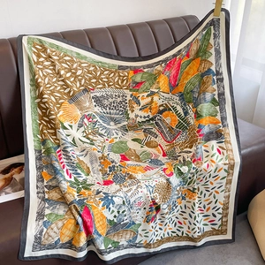 Artistic floral printed silk scarf draped over a classic dark brown leather sofa edge