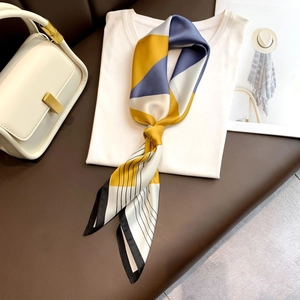 Dettaglio foulard in seta con stampa geometrica blu e gialla annodato come sciarpa chic