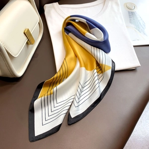 Dettaglio di un foulard in seta con design color block geometrico blu navy e giallo