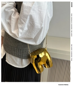 Macro shot of creative golden hip-shaped crossbody bag with glossy metallic finish and chain