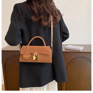 Gros plan d'un sac à bandoulière marron vintage avec fermoir doré et breloque mode