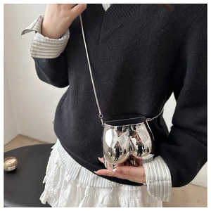Close-up of a silver mirror-finish butt-shaped mini crossbody bag with a fine chain strap
