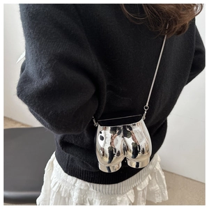 Close-up of creative silver metallic butt-shaped crossbody bag with slim chain strap