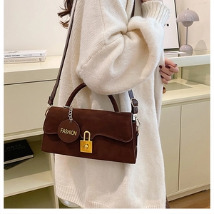 Détail d'un petit sac à main carré marron avec cadenas doré et étiquette FASHION