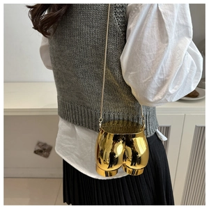 Artistic gold butt-shaped metal crossbody bag with chain strap shown on a model
