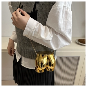Artistic gold human-shaped crossbody bag shown on a model with metallic chain strap