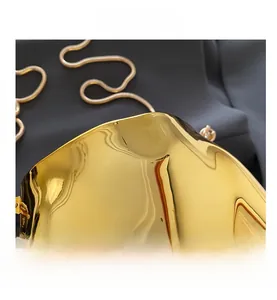 Detailed macro shot of a golden irregular metallic handbag with a sleek snake chain