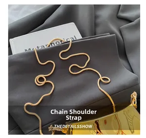 Detail of elegant gold snake chain strap on a metallic mirrored crossbody bag