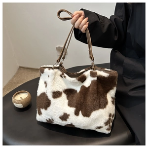 Detail der flauschigen Kunstfell-Tasche mit Kuhmuster und braunen Ledergriffen