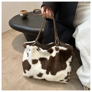 Détail du sac cabas en peluche à motif vache avec poignées en cuir marron