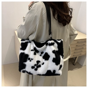 Detail of plush cow print tote bag with soft faux fur texture and black shoulder strap
