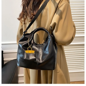 Detail of black soft PU leather tote bag with stylish yellow mini bag charm accessory