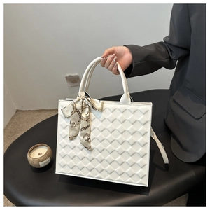 Close-up of white quilted crossbody bag with elegant chain pattern silk scarf detail