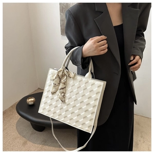 Close-up of white quilted tote bag with square texture and silk scarf handle detail