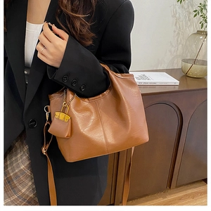 Brown leather bucket bag styled with a black blazer and long shoulder strap