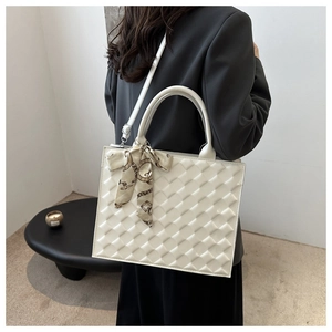 Detail of white quilted tote bag with decorative scarf handle and textured pattern