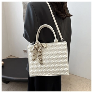 Quilted white square handbag with silk scarf detail and adjustable strap shown on model