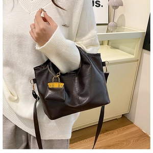 Close-up of deep brown tote bag with pebble leather texture and yellow mini charm