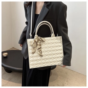 Close-up of white quilted tote bag featuring a decorative vintage chain print silk scarf