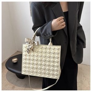 Detailed close-up of cream quilted handbag featuring a chic silk scarf on handle