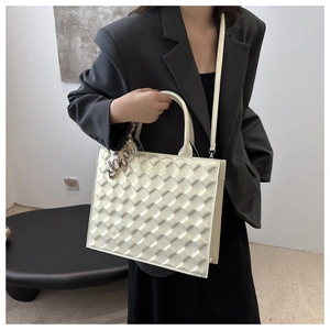 Detail of white quilted tote bag with silk scarf handle on grey blazer outfit