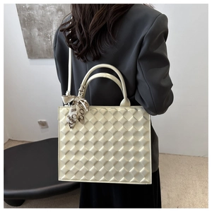 Detail of cream quilted crossbody bag featuring elegant silk scarf on the handle