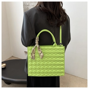 Close-up of bright green quilted tote bag with decorative silk scarf on handle
