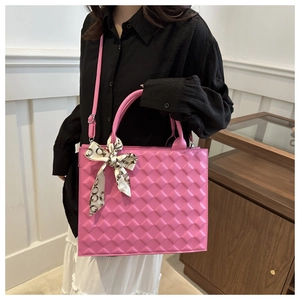 Detail of pink quilted handbag featuring a decorative silk scarf on handle and crossbody strap