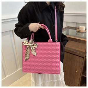 Detail of pink quilted handbag with silk scarf handle on model in stylish interior