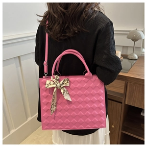 Close-up of bright pink quilted crossbody bag featuring elegant silk scarf handle decoration