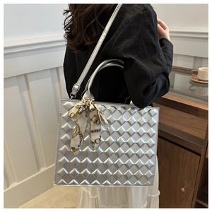 Detail view of silver quilted crossbody bag with decorative silk scarf on handles