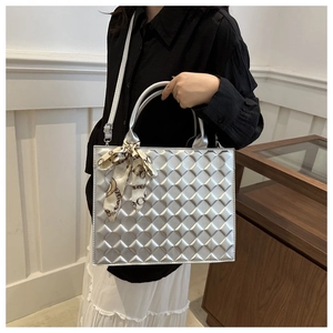 Detail of silver quilted texture handbag with metal ring handle and silk scarf decor