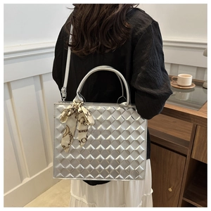 Silver quilted tote bag with silk scarf on handle shown on model's shoulder side view