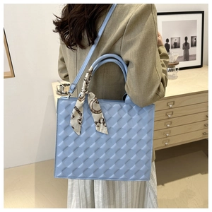 Macro shot of light blue quilted leather texture with silk scarf on handbag handle