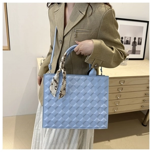 Detail of light blue quilted crossbody bag with decorative silk scarf and adjustable strap