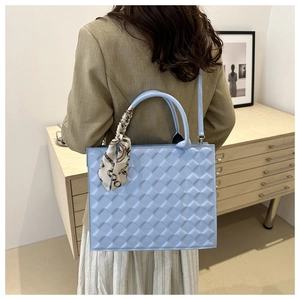 Detailed close-up of light blue quilted crossbody bag with decorative silk scarf