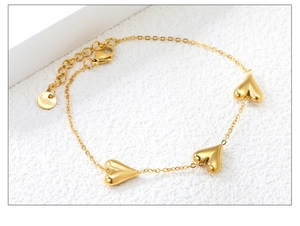 Detailed macro view of 18K gold plated stainless steel heart charm bracelet and lobster clasp