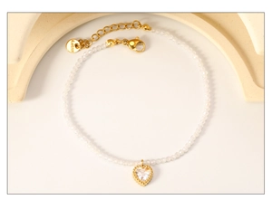 Dettaglio di bracciale con perline, ciondolo a cuore in zircone e chiusura in acciaio
